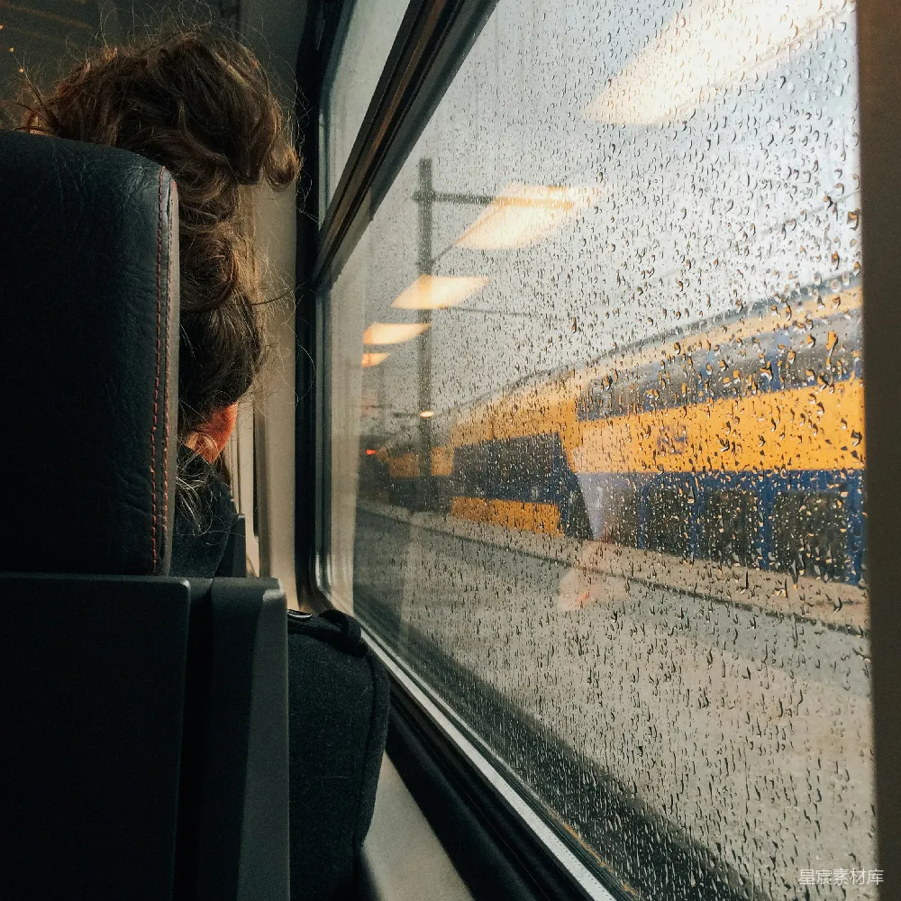 高清摄影 一个女人在雨天透过火车车窗向外看。
