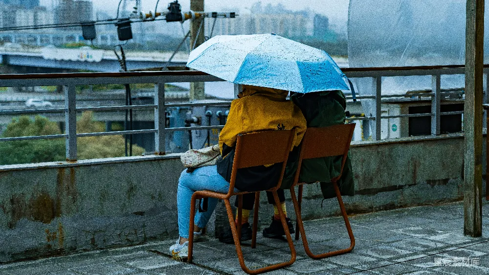 高清摄影 穿着蓝色直筒牛仔裤的女人坐在棕色木椅上，手中拿着伞。