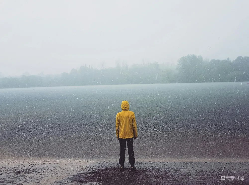高清摄影 站在海边面对着海洋的男人正在雨中站立。
