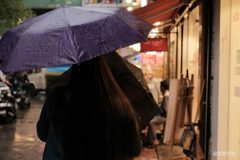高清摄影 一个女子走在街上，手中拿着一把紫色的伞