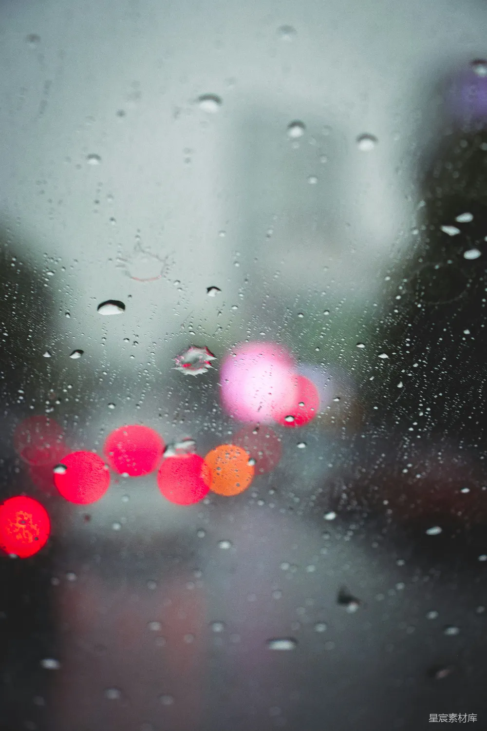 高清摄影 雨中的一张模糊街道照片，有交通灯在其中。