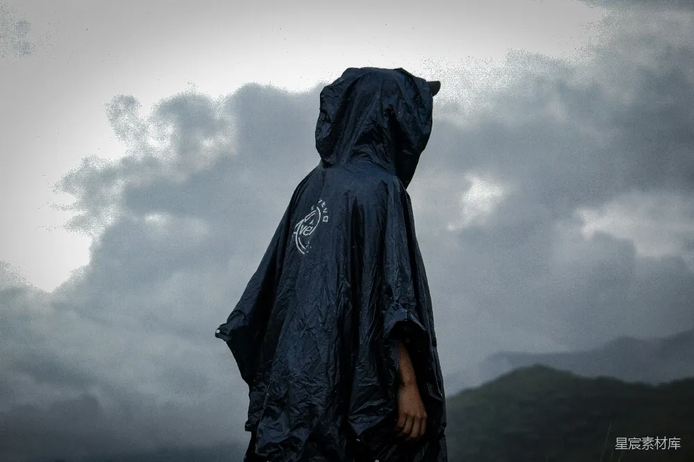 高清摄影 黑色雨衣的人在雨中漫步。