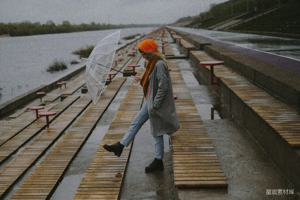 高清摄影 一个撑着雨伞的女人走在木板步行道上