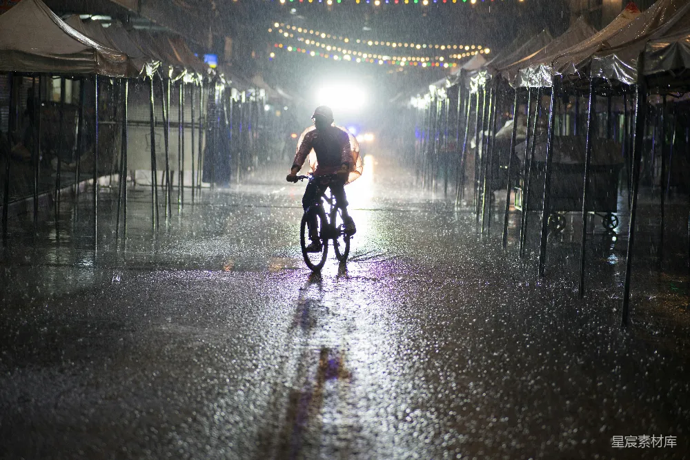 高清摄影 一个男子在一条雨水浸湿的街道上骑自行车