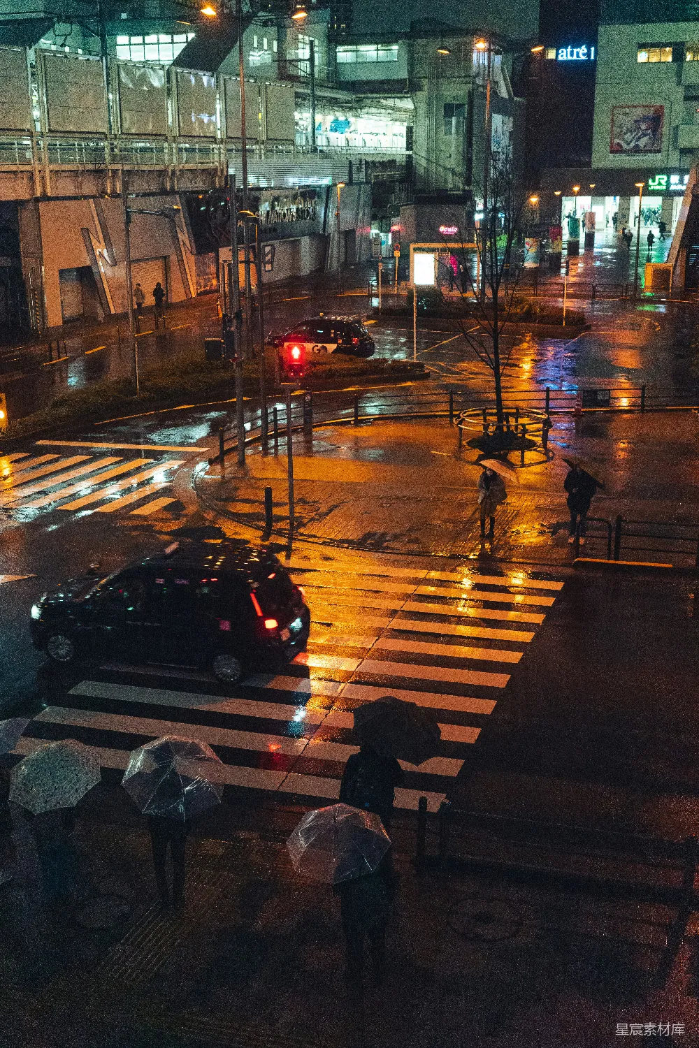 高清摄影 夜晚持伞的人们穿过湿漉漉的街道。