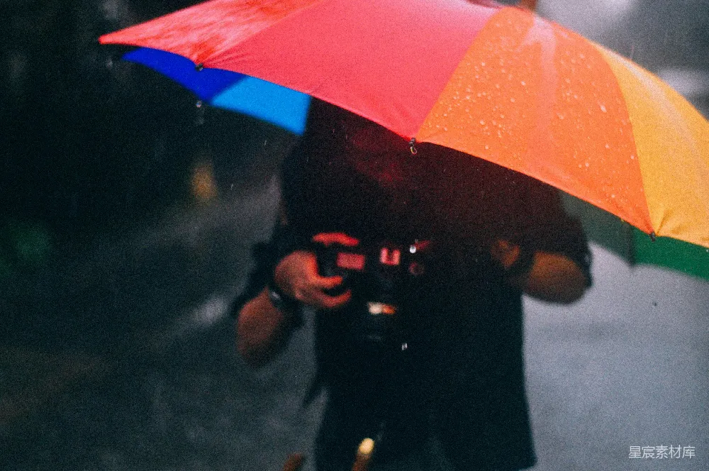 高清摄影 手持相机并打着彩色伞的男人站在雨中