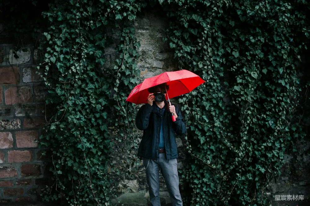 高清摄影 穿着黑色夹克的男人手持红色雨伞
