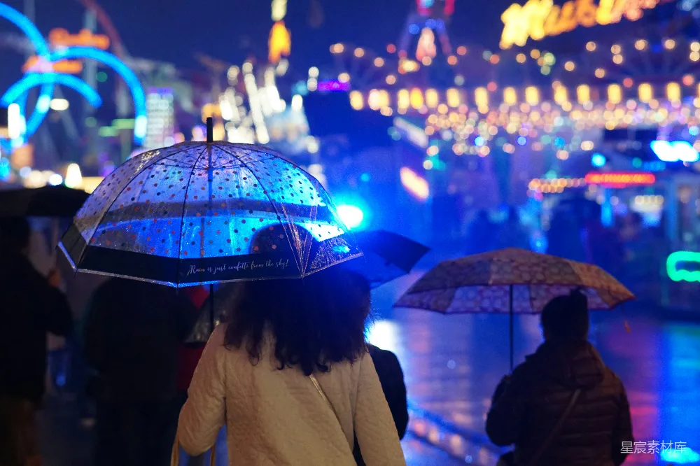 高清摄影 人们在一座明亮的嘉年华中使用雨伞。