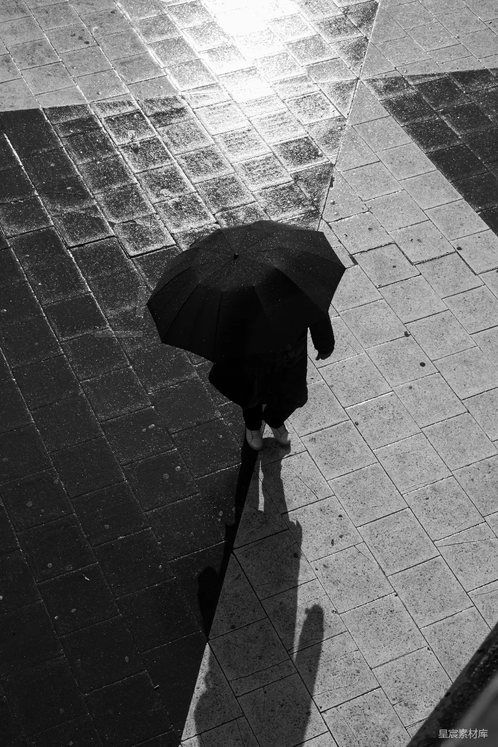 高清摄影 一个人在雨中走在人行道上，手中持着一把伞。