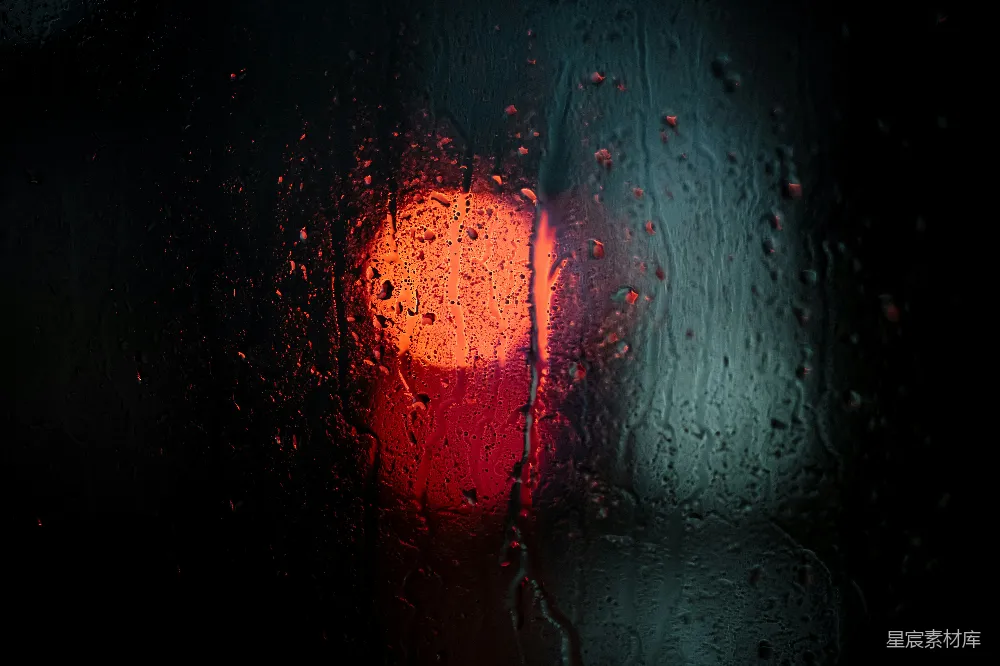 高清摄影 红灯静静地躺在蒙着雨的窗户的一侧。