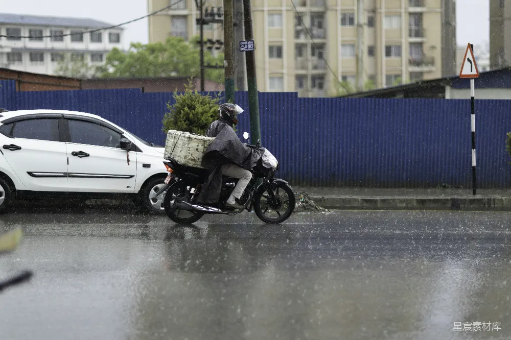 高清摄影 一个人在雨中骑摩托车前行。