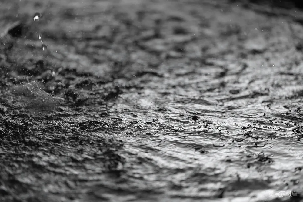高清摄影 雨滴在暗色且有纹理的表面上形成涟漪。