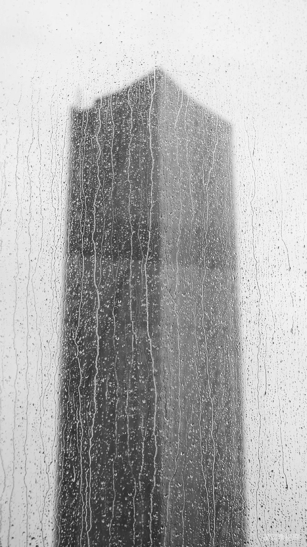 高清摄影 透过蒙上雨的窗户可以看到一座高耸的建筑物。