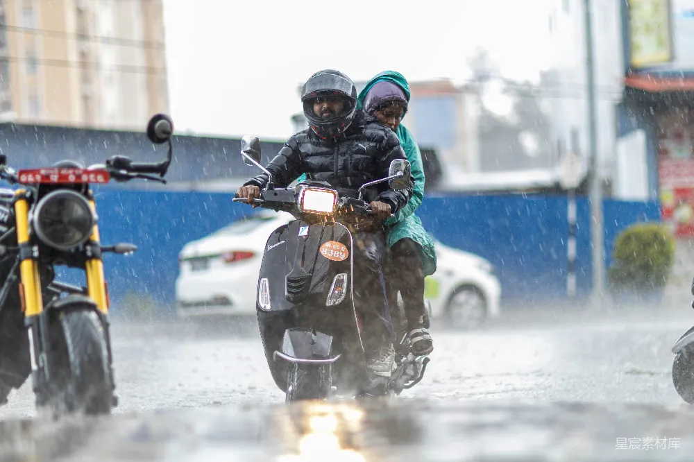 高清摄影 两个人在雨中骑着一辆滑板车。