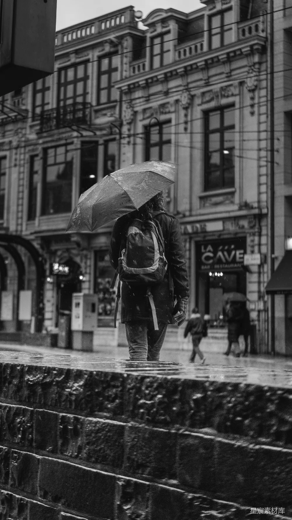 高清摄影 拿着雨伞的人在城市街道上行走着。