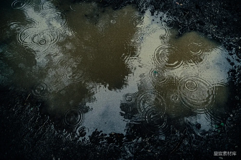 高清摄影 雨滴在泥泞的水洼中荡起涟漪，映射着天空。