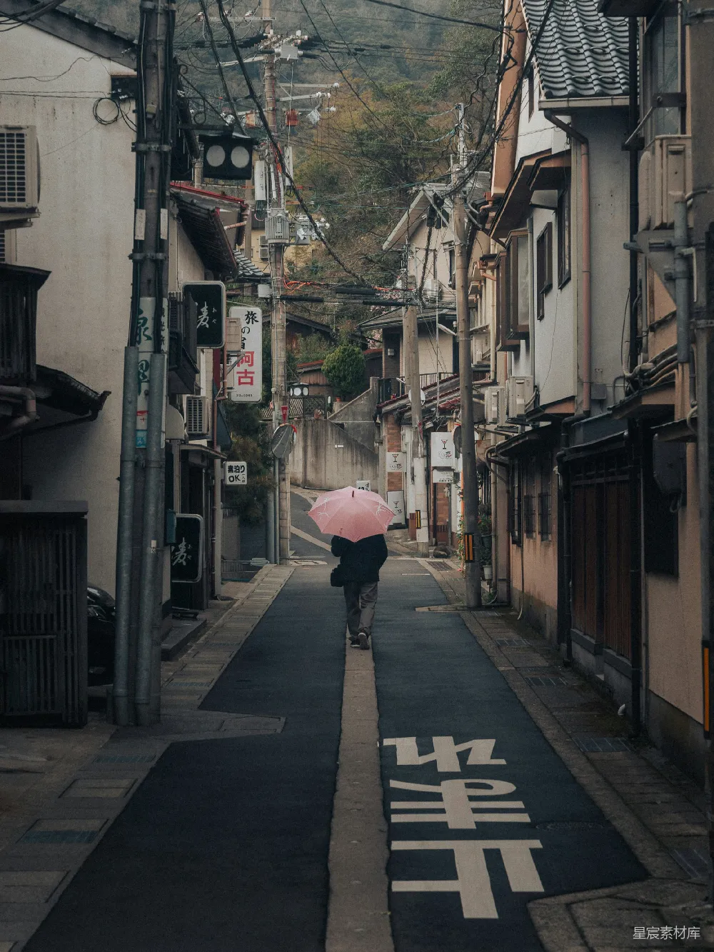 高清摄影 身穿粉红色雨伞的人走在狭窄的街道上。