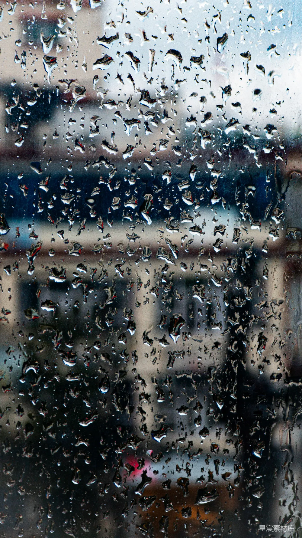 高清摄影 窗户上的雨滴与模糊的建筑物。