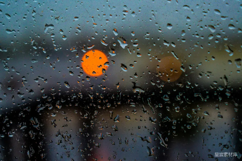 高清摄影 窗户上的雨滴与模糊的橙色灯光