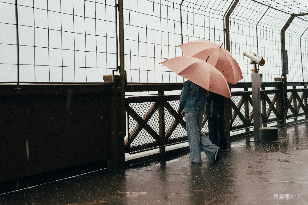 高清摄影 两个带着粉色伞的人在雨中观景台观察。