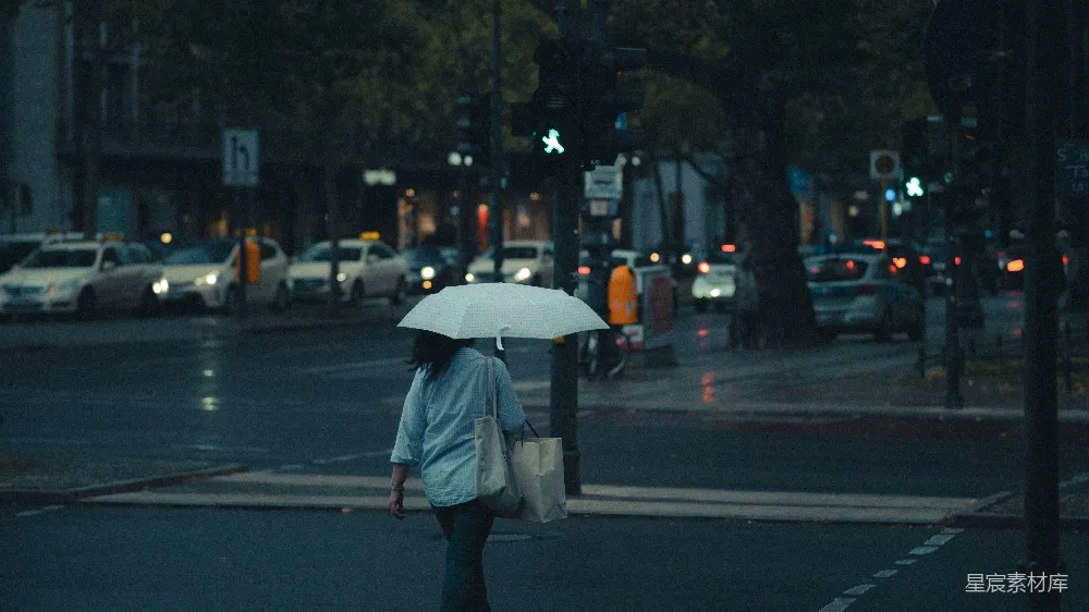 高清摄影 身穿灰色夹克的男人手持雨伞在夜晚街道上行走