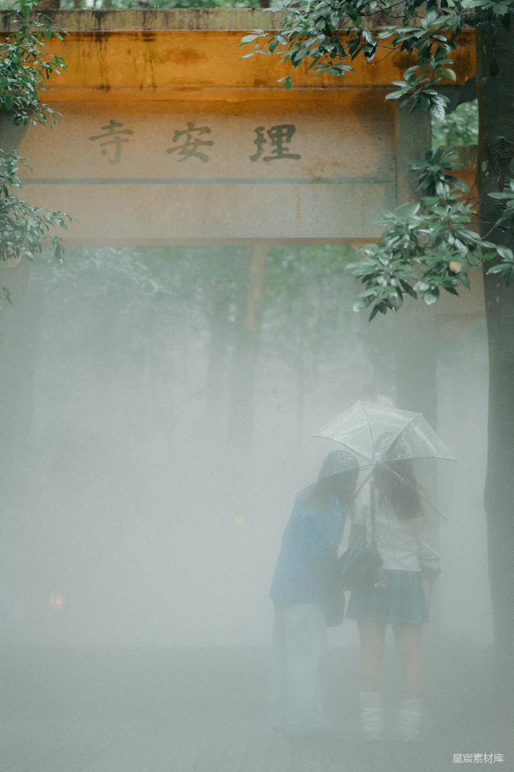 高清摄影 两个人打着伞穿过雾气中的庙门