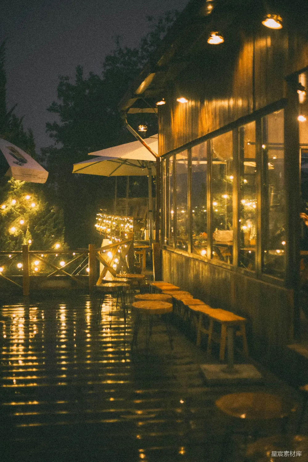 高清摄影 夜晚的室外咖啡馆，挂着串灯和倒影
