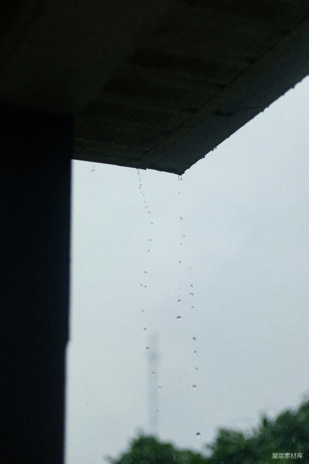 高清摄影 屋顶檐口处的雨滴在灰色的天空下落下。