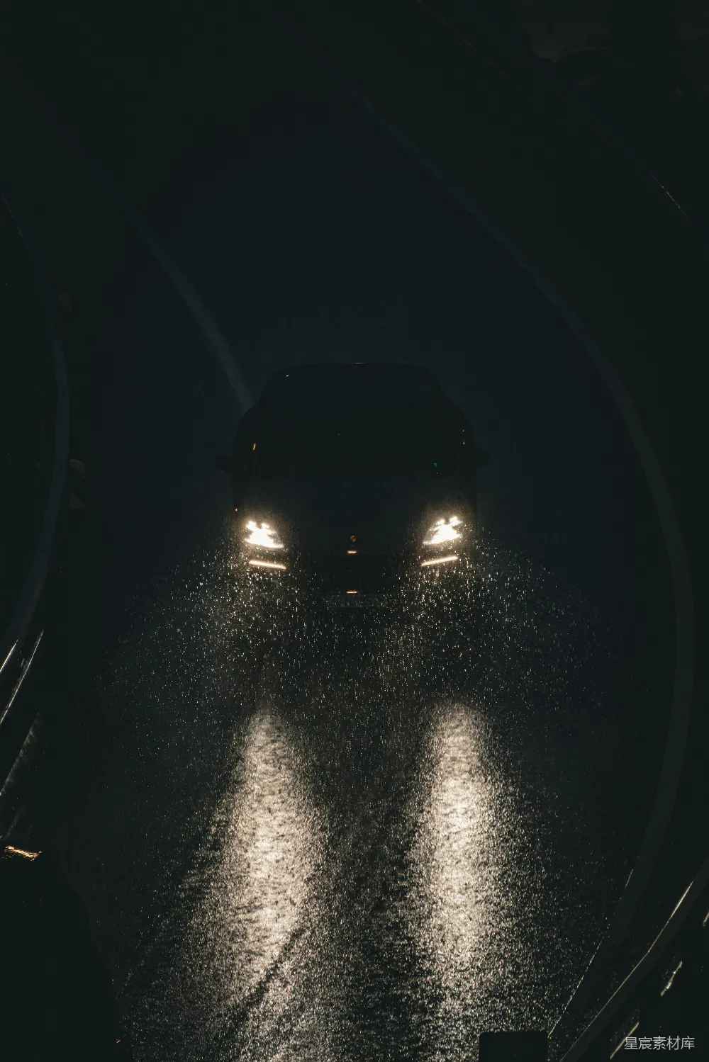 高清摄影 汽车大灯在夜间照亮一条湿滑的道路。
