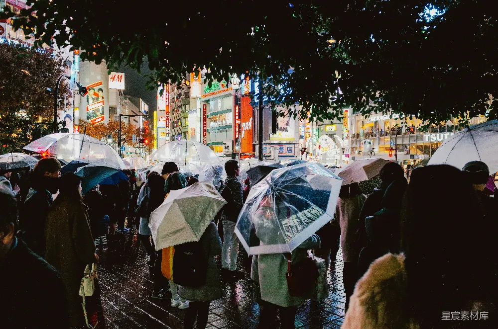 高清摄影 夜晚，人们打着伞走在雨中的城市里。