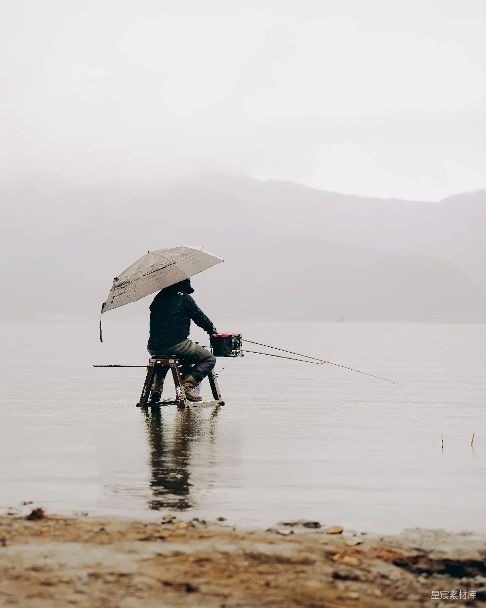 高清摄影 人在雾天撑伞钓鱼的场景。