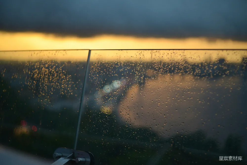 高清摄影 玻璃栏杆上的雨滴与日落背景。