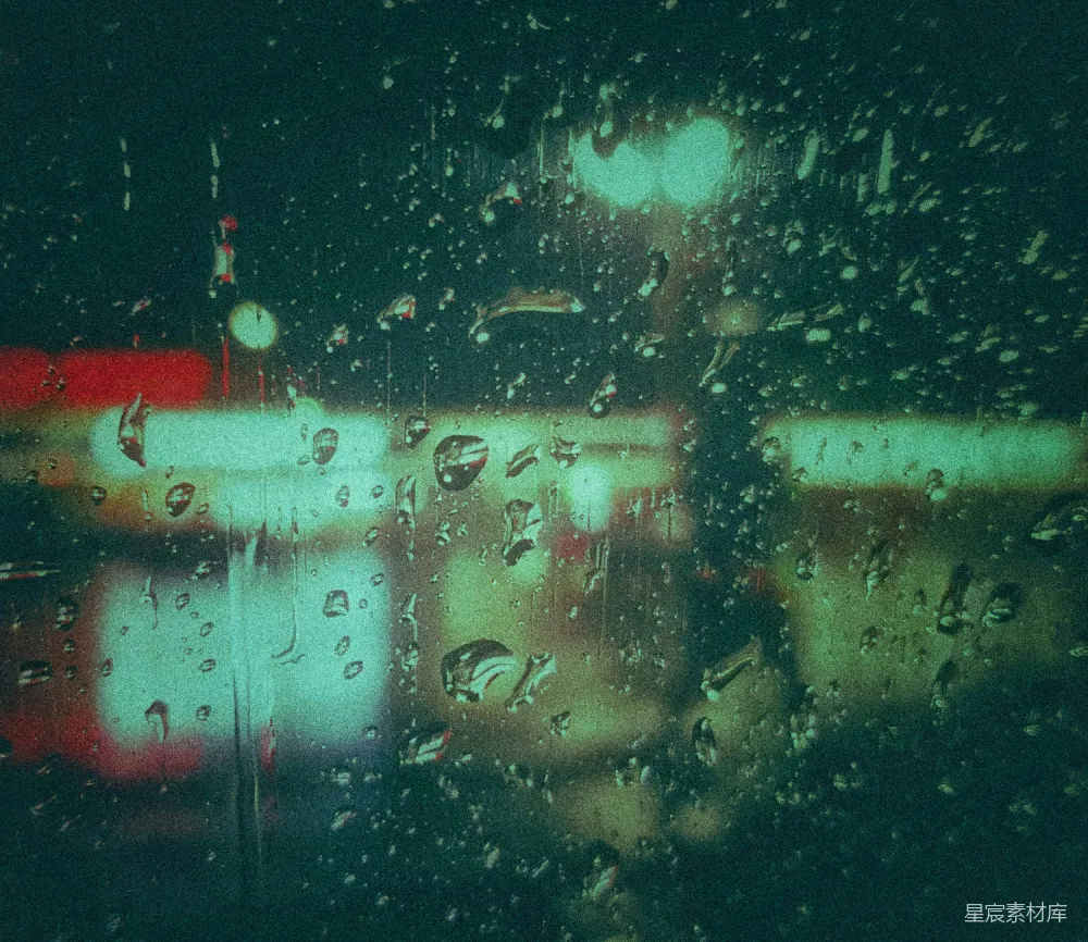 高清摄影 夜幕下的窗玻璃上挂着几滴雨水，映照着模糊的城市灯光。