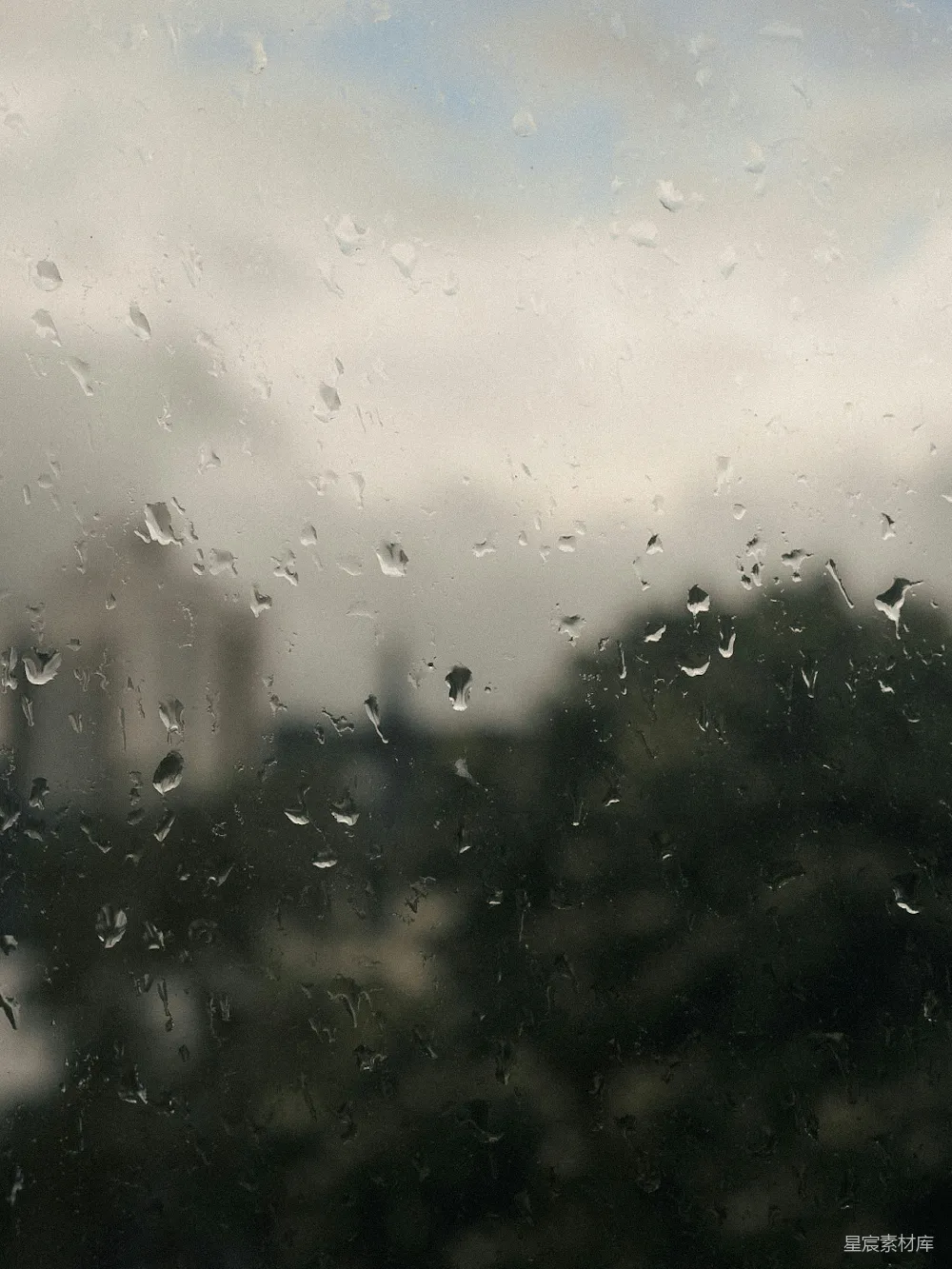 高清摄影 窗前滴水，模糊的树木和建筑。