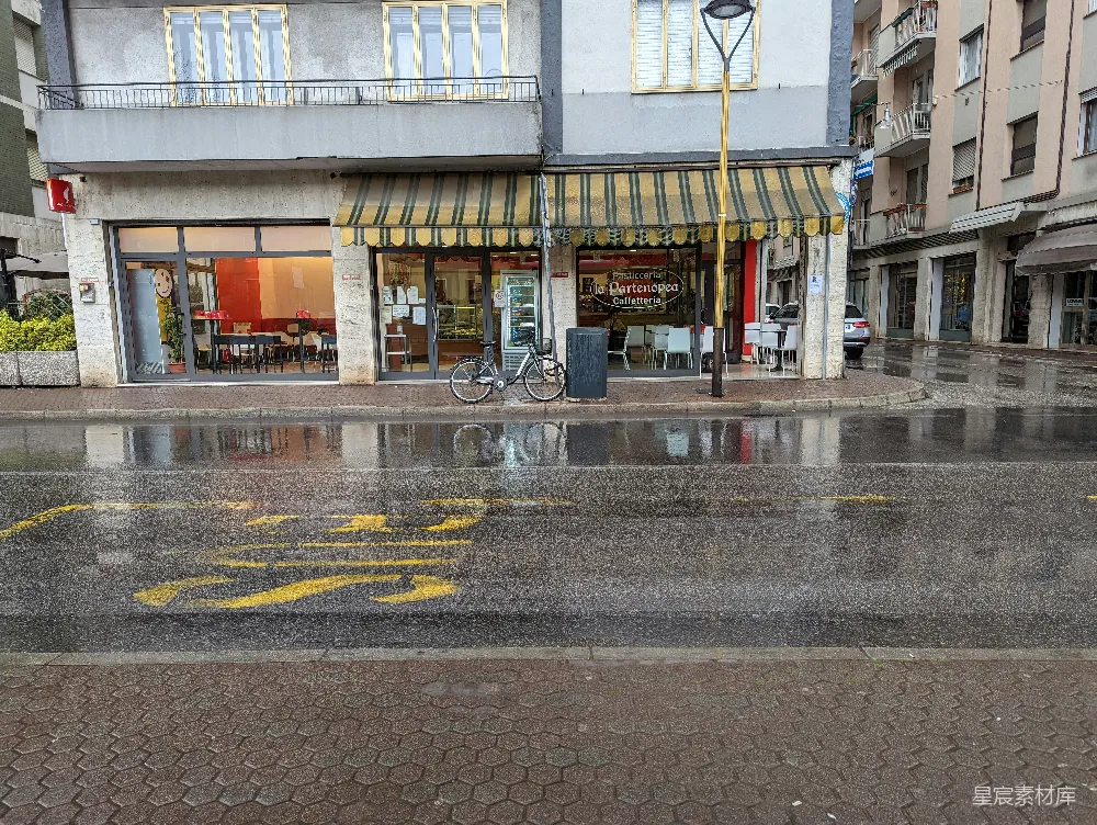 高清摄影 前面一栋建筑前有一条湿漉漉的街道，一辆自行车停在那前方。