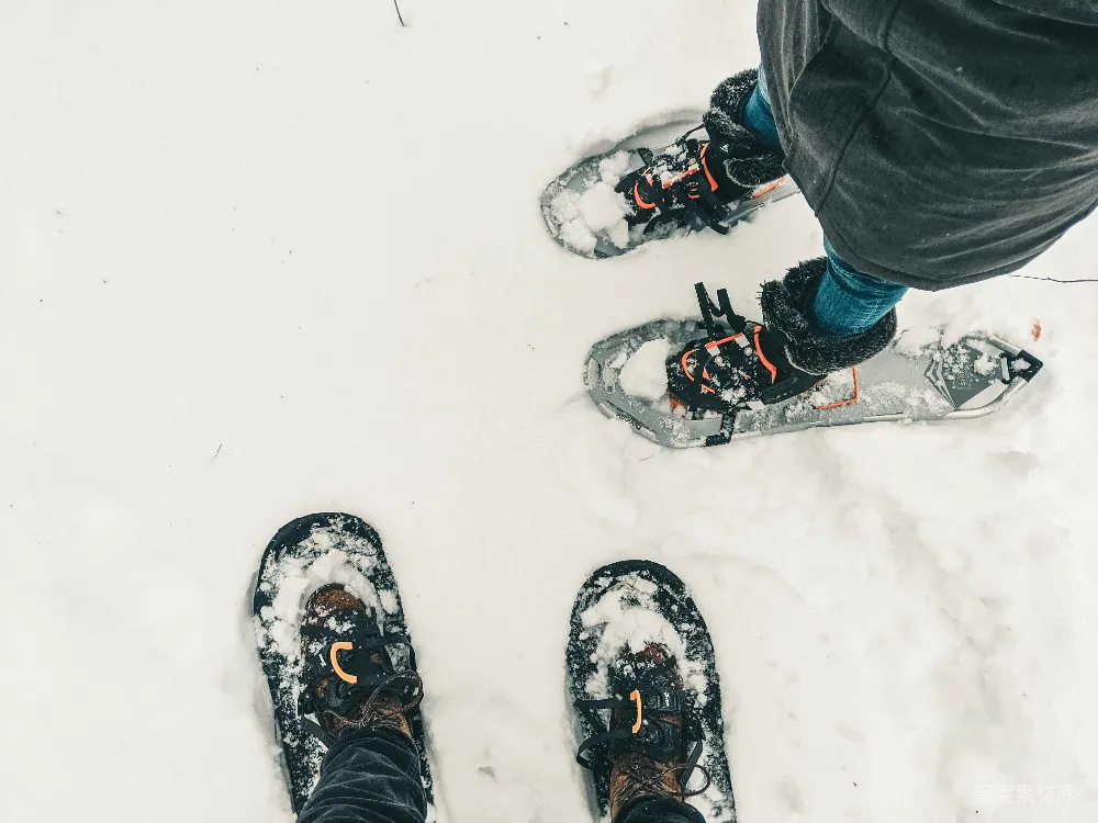 高清摄影 黑色裤子和黑白雪地靴的人站在覆盖着积雪的地面上