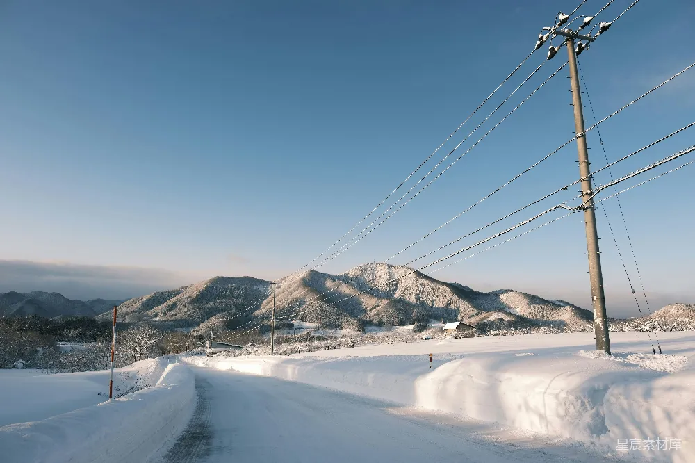 高清摄影 覆盖着白雪的道路，背景是电线和山脉。