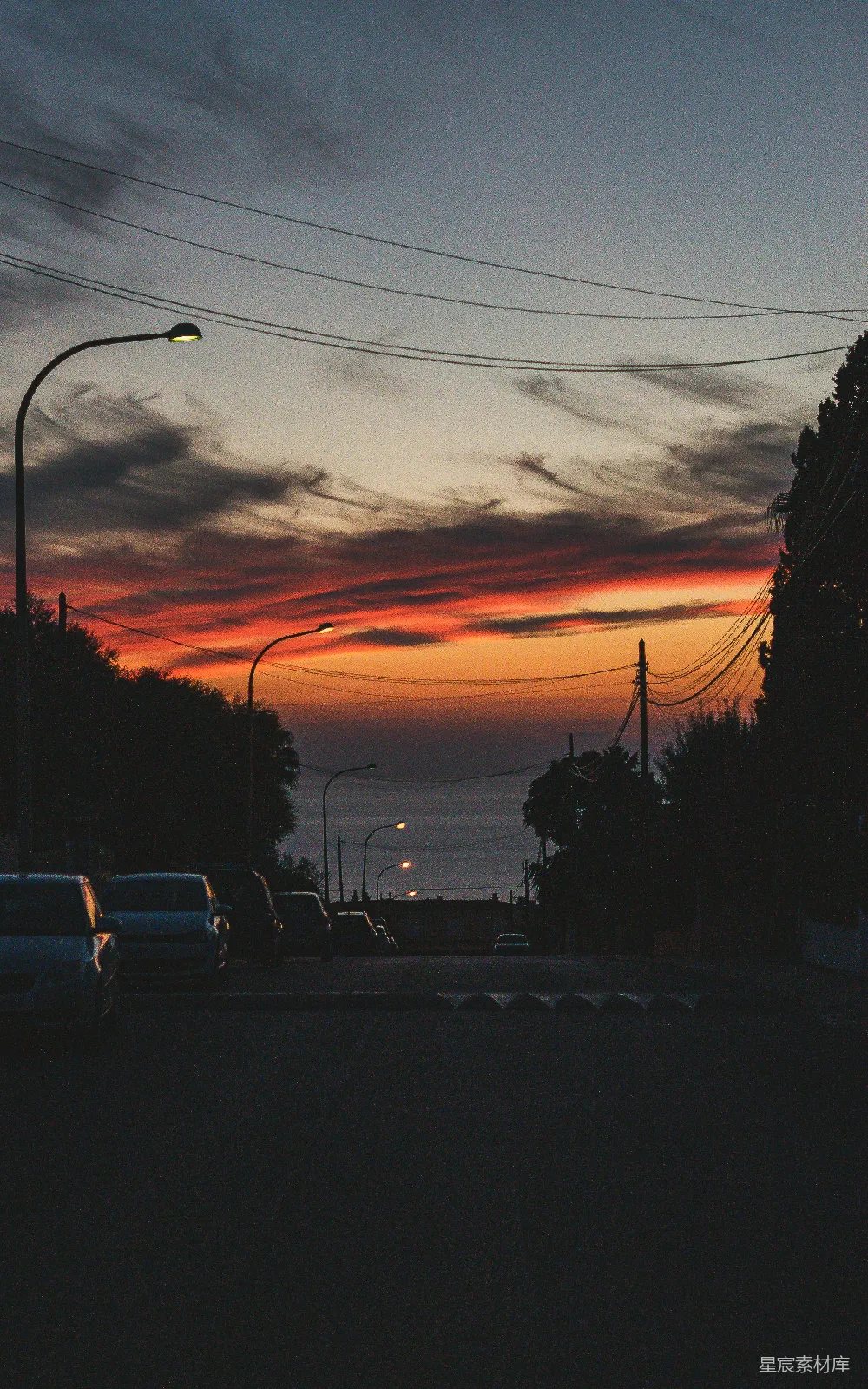 夕阳下的街道景色，两侧停有汽车。