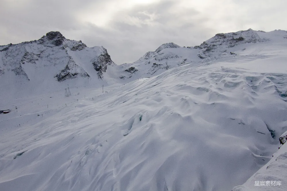 高清摄影 远处一座被雪覆盖的山峦和一条缆车轨道在其中显现。