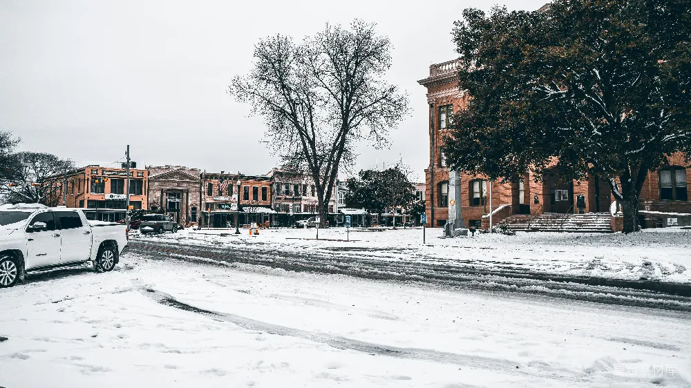 高清摄影 一辆白色卡车在覆有白雪的街道上行驶。