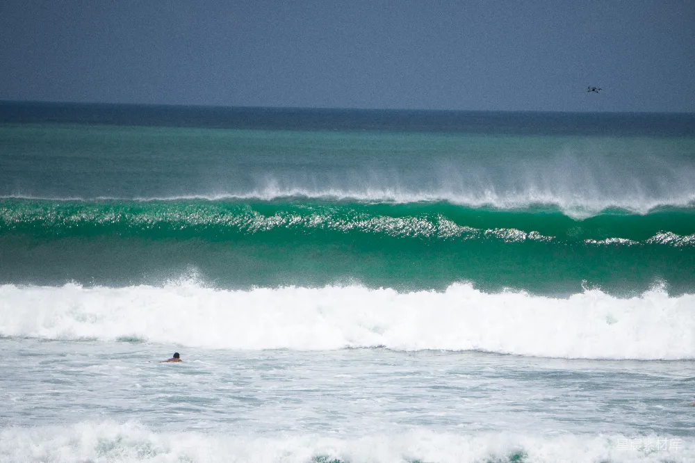 高清摄影 海边一个骑着冲浪板的人在波浪上。