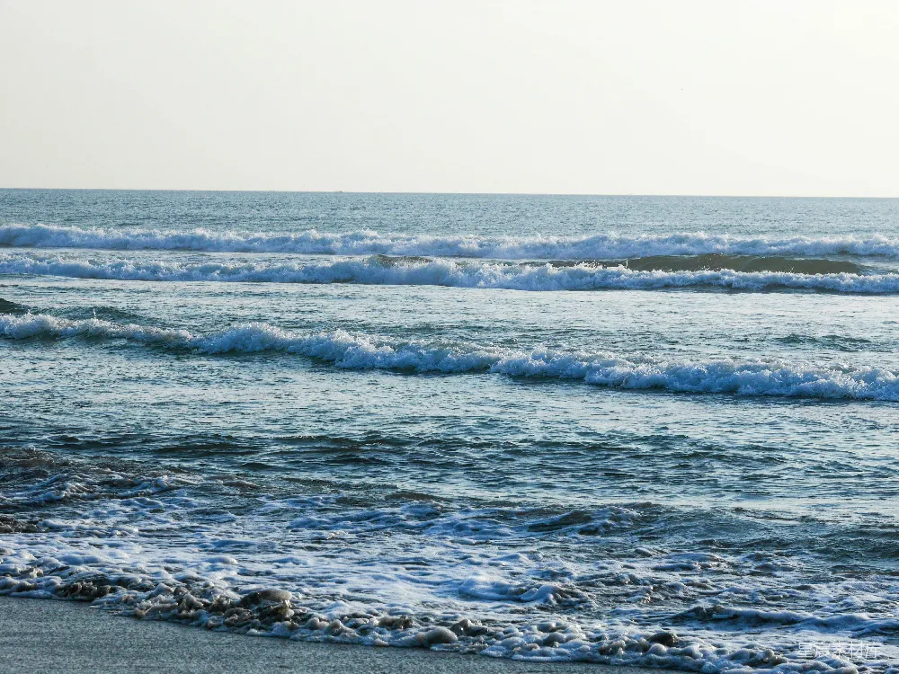 高清摄影 一个骑着冲浪板的人漂浮在波涛汹涌的海滩上