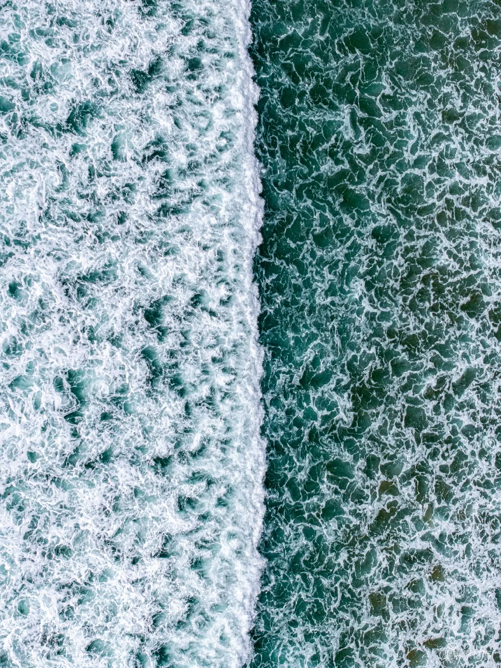 高清摄影 破碎的海浪与波光粼粼的绿水相接。