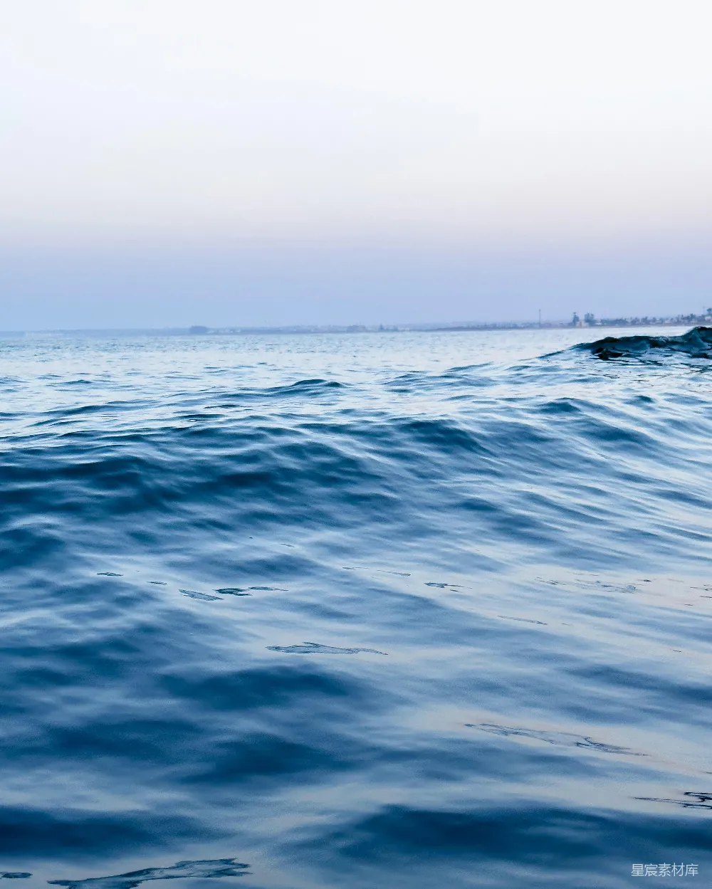 高清摄影 海边一个人坐在冲浪板上在海浪上滑行