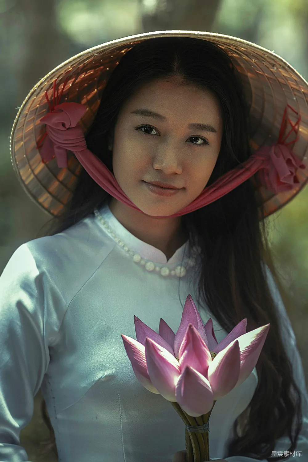高清摄影 身穿白色长袖连衣裙并佩戴褐色头巾的女士手持粉红色花瓣花。