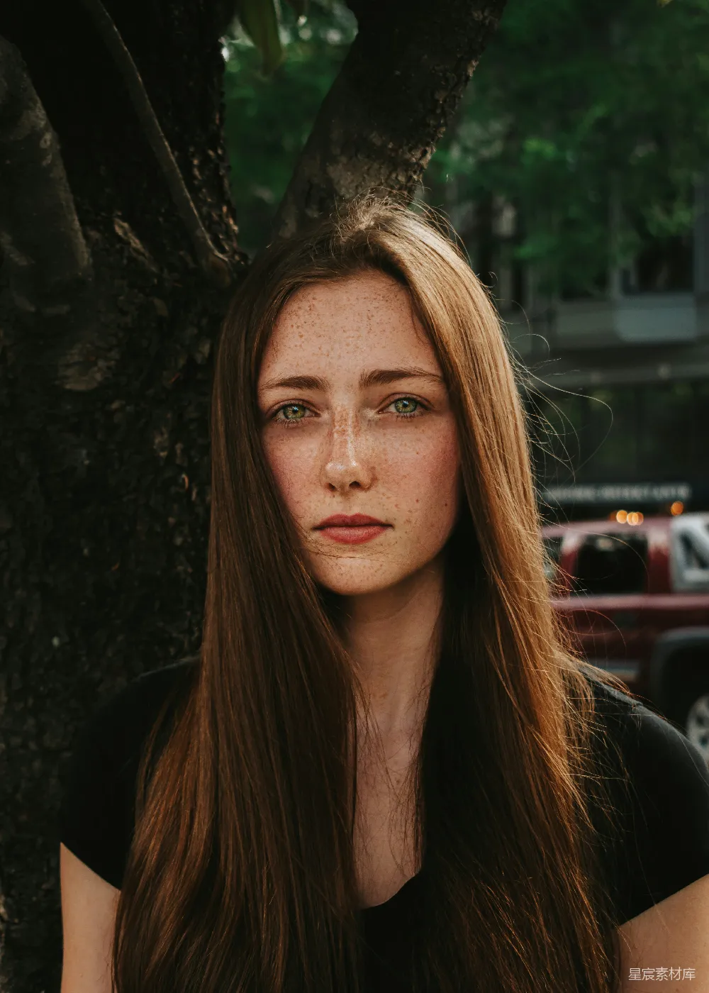 高清摄影 一个头发带有雀斑的妇女坐在树下。