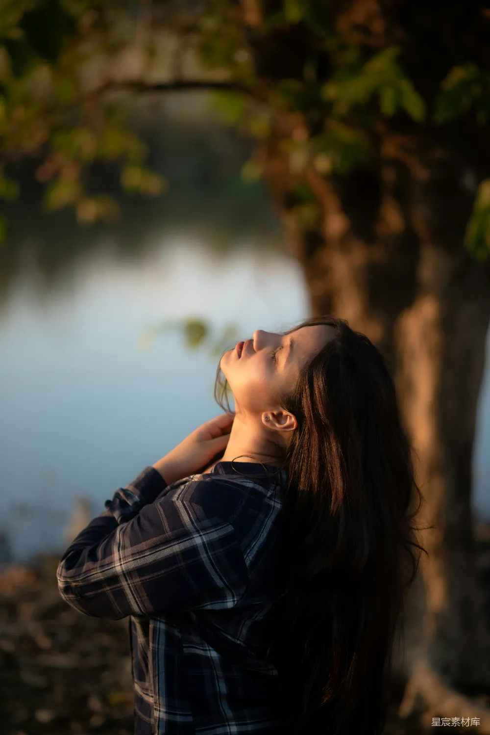 高清摄影 一个女人站在树旁闭着眼睛。