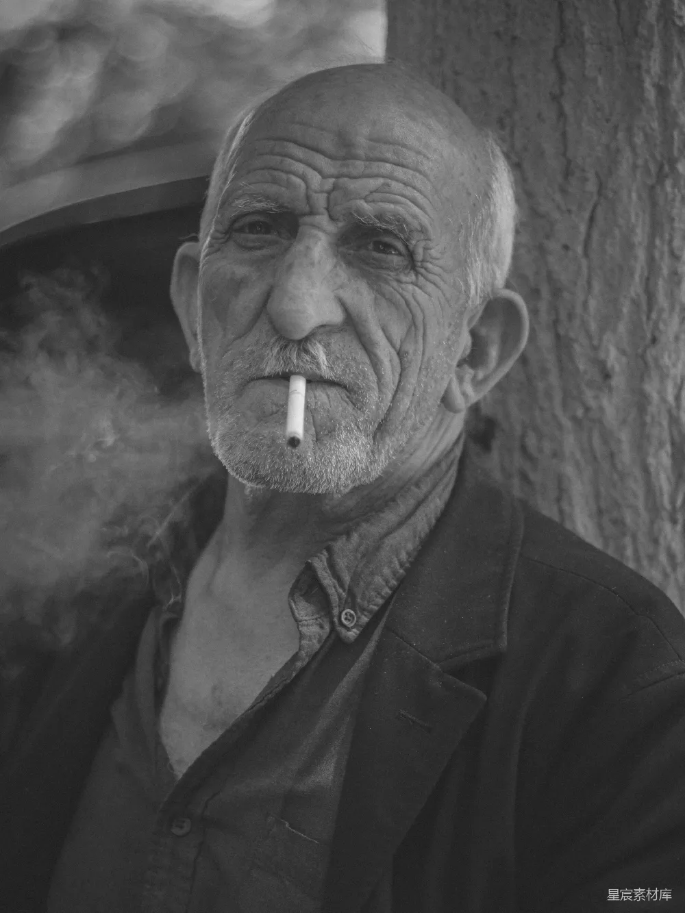 高清摄影 路边一棵树旁的男人正在抽烟。