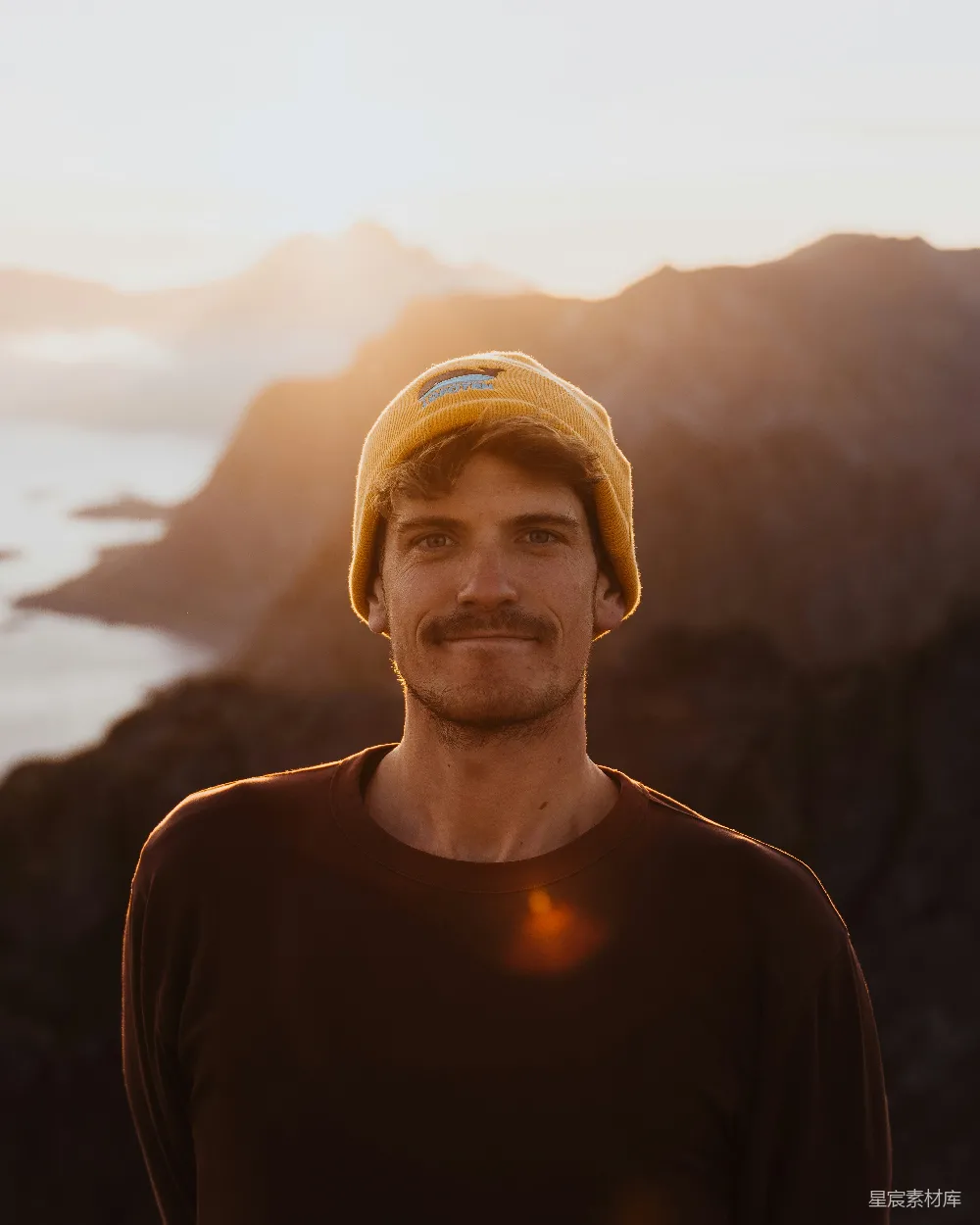 高清摄影 一个戴黄色帽子的男人站在山前。