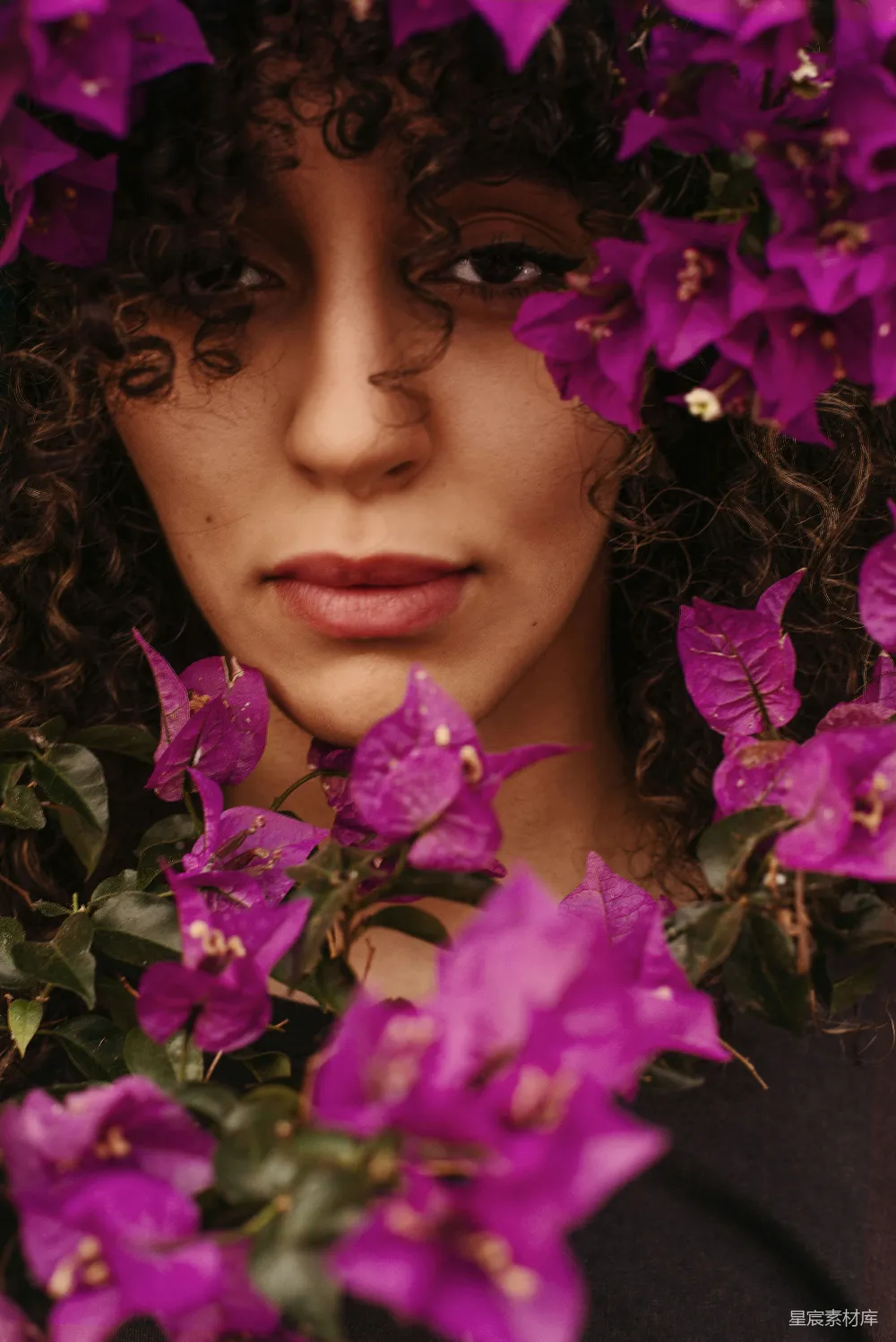 高清摄影 人物 实验性 一头 curly 头发的女子，头上戴着紫色的花朵。